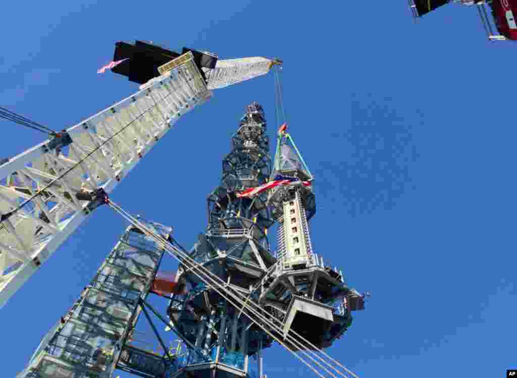 The silver spire topping One World Trade Center is lifted as it is fully installed on the building&#39;s roof, bringing the structure to its full, symbolic height of 1,776 feet (541 meters), May 10, 2013 in New York.