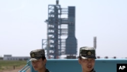 FILE - Chinese soldiers stand guard near the assembly of the Long March 2F rocket and the Shenzhou 10 spacecraft at the Jiuquan Satellite Launch Center in Jiuquan in northwest China's Gansu Province .