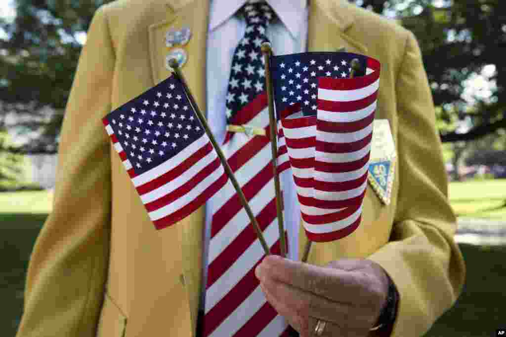 Navy veteran William Englert passes out U.S. flags to the crowd attending Memorial Day ceremonies at Arlington National Cemetery, May 25, 2015.&nbsp;