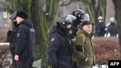 Sankt-Peterburqda polis əməkdaşları mərhum rus müxalifət lideri Aleksey Navalnının xatirəsinə gül dəstələri qoymaq üçün siyasi repressiyaların qurbanlarının xatirəsinə ucaldılmış abidəyə gələn bir nəfəri saxlayıb. 17 fevral, 2024. 
