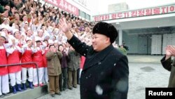 Pemimpin Korea Utara Kim Jong-un melambaikan tangan pada para pekerja dalam kunjungan ke pabrik makanan anak-anak, dalalm foto yang dirilis oleh kantor berita Korea Utara KCNA 16 Desember 2014.