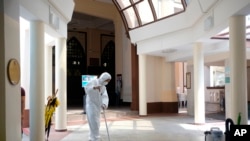 A man wearing protective suit and mask mops the floor inside the Hajjah Fatimah mosque, in Singapore, March 13, 2020.
