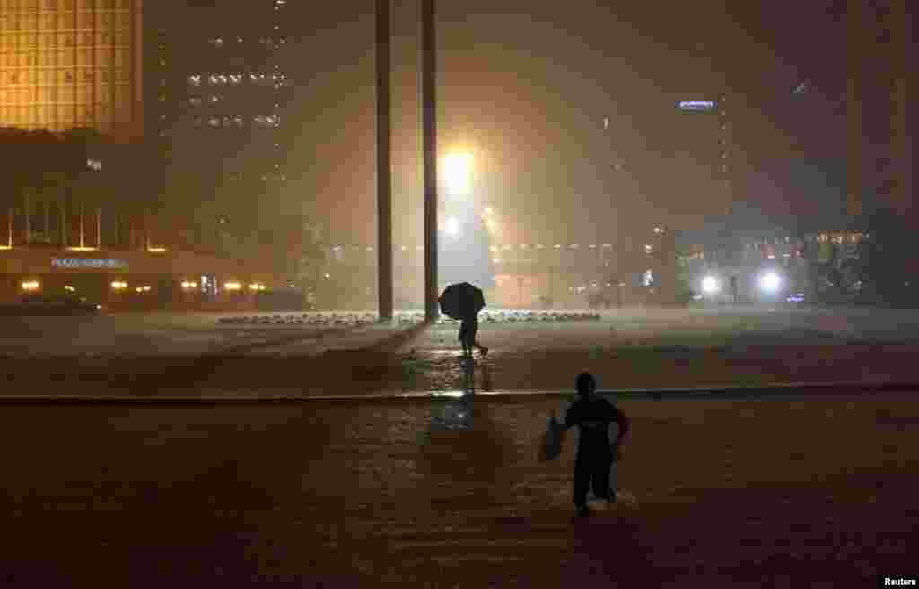 People walk on the Bundaran Hotel Indonesia roundabout during flooding in Jakarta, January 17, 2013. 