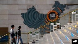 A family walks by a map showing Evergrande development projects in China at an Evergrande city plaza in Beijing, Sept. 21, 2021.(AP Photo/Andy Wong)