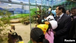 Taiwan President Ma Ying-jeou is accompanied by children as he looks at Tuan Tuan and Yuan Yuan inside their new enclosure at the Taipei City Zoo, January 24, 2009.