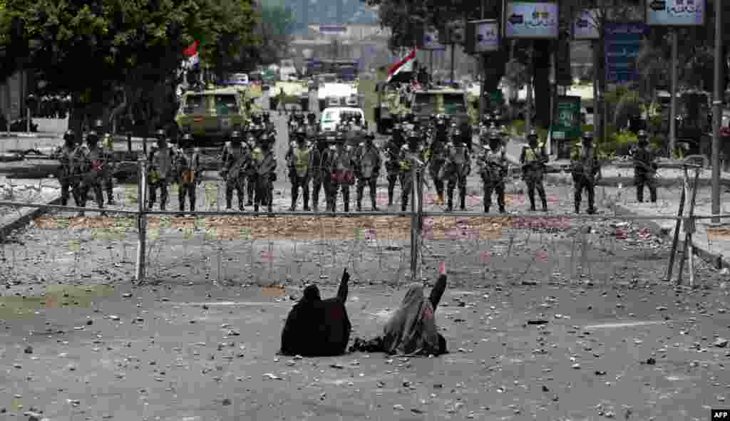 Para pendukung Presiden Mesir&nbsp; yang terguling Mohamed Morsi duduk di depan pagar kawat berduri yang menghalangi akses ke markas Garda Republik di Kairo.