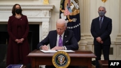 FILE - President Joe Biden signs executive orders as part of the U.S. COVID-19 response as Vice President Kamala Harris (L) and Director of NIAID Anthony Fauci look on, in the State Dining Room of the White House in Washington, Jan. 21, 2021. 