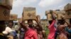 Des habitants du bidonville d'Oworonshoki portent leurs colis alimentaires distribués par la Lagos Food Bank Initiative, le 10 juillet 2021. (Photo AP/Alamba Sunday)