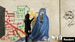 Afghan artist Malina Suliman paints graffiti on a wall in Kandahar city December 30, 2012.