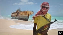 FILE - Masked and armed Somali pirate Hassan stands near a Taiwanese fishing vessel washed ashore after the pirates were paid a ransom and the crew were released.