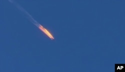 FILE - This frame grab from video by Haberturk TV, shows a Russian warplane on fire before crashing on a hill as seen from Hatay province, Turkey, Nov. 24, 2015.