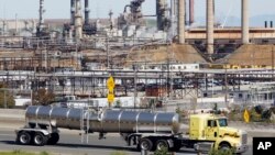 FILE - In this March 9, 2010, photo, a tanker truck passes an oil refinery in Richmond, California. Vowing to keep the United States on track to meet its emissions-cutting target, an alliance of states, cities and businesses have pledged to stay in the climate-change fight despite the Trump administration's recent withdrawal from the Paris climate accords. 