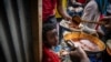 File - Elena, 7, center, lines up with other displaced Tigrayans to receive food donated by local residents at a reception center for the internally displaced in Mekele, in the Tigray region of northern Ethiopia, May 9, 2021. 