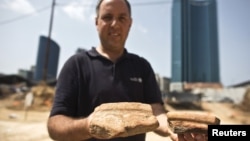 Diego Barkan, director of the excavation for the Israel Antiquities Authority, shows fragments of ancient basins unearthed at an archaeological dig in a future construction site in Tel Aviv, March 29, 2015. 