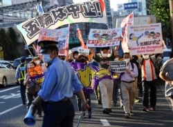 Anti-Olympics group's members wearing protective face masks display banners during their protest march, amid the COVID-19 pandemic at Shinjuku district in Tokyo, Japan, Aug. 1, 2021.
