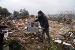 Seorang pria Palestina membawa foto keluarga di reruntuhan sebuah rumah yang dihancurkan oleh pemerintah kota Yerusalem, di Sheikh Jarrah, Yerusalem timur Rabu, 19 Januari 2022.
