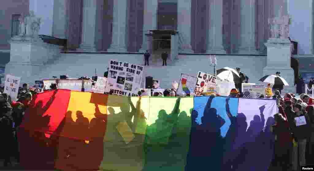 Anti-Proposition 8 protesters are shadowed by a rainbow banner in front of the U.S. Supreme Court in Washington, March 26, 2013.