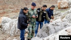 A Lebanese army personnel inspects the remains of a shell that was launched from Lebanon to Israel, which according to activists landed 500m from the Lebanese-Israeli border, in the southern Lebanese village of Sarada, Dec. 29, 2013. 