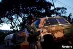 Eduardo Liendo, 63, who lives inside an old car, holds his prize money which he won on "Los Animalitos" (or the Little Animals) betting game on the outskirts of Caracas, Venezuela, October 11, 2017.