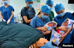 Para perawat memperlihatkan bayi kembar yang lahir dari program bayi tabung kepada ibu mereka (bawah) di sebuah rumah sakit di Xi’an, Provinsi Shaanxi, 16 Agustus 2012.
