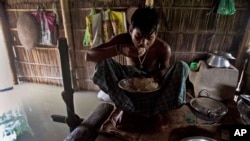 FILE - A boy eats rice inside his house in India, which is partially submerged in floodwater, Sept. 2, 2015.