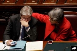 Italian Prime Minister Paolo Gentiloni talks with his Minister of Relations Anna Finocchiaro after giving his first speech as prime minister, Tuesday, Dec. 13, 2016.