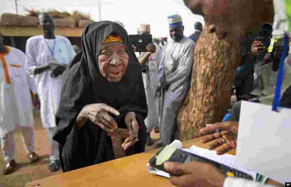 Seorang perempuan tua Nigeria tiba di TPS untuk melakukan validasi kartu pemilih menggunakan pemindai sidik jari, di Daura, Nigeria (28/3). (AP/Ben Curtis)