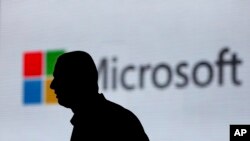 FILE - A man is silhouetted as he walks in front of a Microsoft logo Nov. 7, 2017. Microsoft says it has uncovered new Russian hacking attempts targeting U.S. political groups ahead of midterm elections in November. (AP Photo/Altaf Qadri, File)