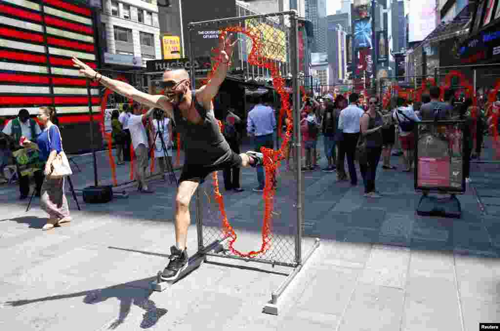 A man leaps through one of a series of 17 sculptures made of copper and steel panels cut out with various sizes of human silhouettes by Cuban-born artist Arles del Rio in New York&#39;s Times Square.