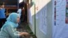 Seorang pemilih memeriksa daftar legislatif yang dipasang di sebuah TPS di Sleman, DIY dalam Pemilu 2019. (Foto: VOA/ Nurhadi)