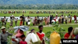FILE - Rohingya refugees, who crossed the border from Myanmar two days before, walk after they received permission from the Bangladeshi army to continue on to refugee camps in Palang Khali, Bangladesh, Oct. 19, 2017.