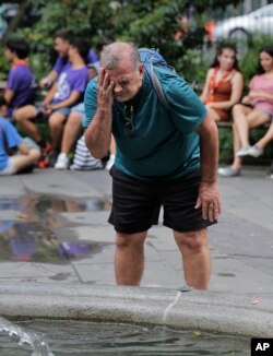 Russ Wilson memercikkan air di wajahnya dari air mancur di New York, 17 Juli 2019. (Foto: dok).