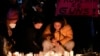 Women place candles at a memorial during a vigil blocks from the Star Ballroom Dance Studio, Jan. 24, 2023, in Monterey Park, Calif., where a gunman killed multiple people amid Lunar New Years celebrations in the predominantly Asian American community.