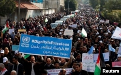 Karyawan Palestina yang bekerja untuk United Nations Relief and Works Agency (UNRWA) mengacungkan poster-poster dalam unjuk rasa memprotes keputusan AS memotong bantuan, di Gaza City, 29 Januari 2018.