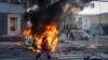 An emergency medical technician walks past a burning car after a Russian missile strike in Kyiv, Ukraine, Oct. 10, 2022. 