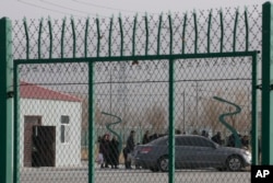 FILE - Residents line up inside the Artux City Vocational Skills Education Training Service Center, which was revealed by leaked documents to be a forced indoctrination camp at the Kunshan Industrial Park in Artux in western China's Xinjiang region, Dec. 3, 2018.