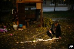 A local man cuts pieces of firewood in Kivsharivka, Ukraine, Sunday, Oct. 16, 2022. (AP Photo/Francisco Seco)