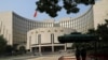 FILE - Paramilitary police officers stand guard in front of the headquarters of the People's Bank of China, the central bank (PBOC), in Beijing, Sept. 30, 2022. 