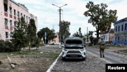 FILE PHOTO: A Ukrainian serviceman patrols a street next to damaged buildings in the town of Sudzha