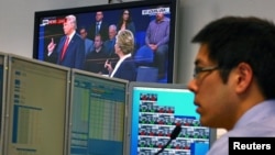 A trader works at his desk as the U.S. presidential town hall debate between Republican U.S. presidential nominee Donald Trump and Democratic nominee Hillary Clinton is shown on TV, at Citibank's trading floor in Sydney, Australia, Oct. 10, 2016.