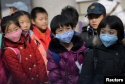 Schoolchildren wear masks as they leave school early at noon due to heavy air pollution, at a primary school in Shenyang, Liaoning province, Nov. 13, 2015.