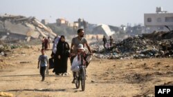 Palestinci koriste stazu obrubljenu uništenim zgradama kampa al-Bureij u središnjem pojasu Gaze 2. juna 2024.