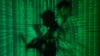 Illustration shows projection of binary code on a man holding a laptop computer, in an office.