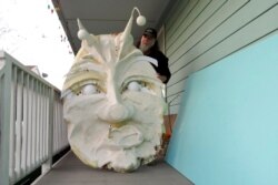 FILE - Thom Karamus shows his papier-mâché head of the hookah-smoking caterpillar from "Alice in Wonderland," Jan. 14, 2021, in New Orleans. All around the city, thousands of houses are being decorated as floats for Mardi Gras.