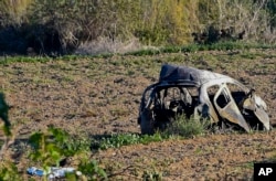 FILE - The wreckage of the car of investigative journalist Daphne Caruana Galizia lies next to a road in the town of Mosta, Malta, Oct. 16, 2017.