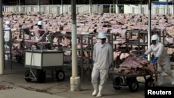 Workers carry salted meat which will be spreaded, dried and then packed at a plant of JBS S.A, the world's largest beef producer, in Santana de Parnaiba, Brazil