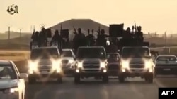 FILE - An image grab taken from a video released by Islamic State group's official Al-Raqqa site via YouTube allegedly shows Islamic State (IS) group recruits riding in armed trucks in an unknown location. 