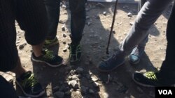 Demonstrating dangers for small children living in this camp, young men point out a dead snake on the ground, nearby Idomeni, Greece, March 30, 2016. (H. Murdock/VOA)