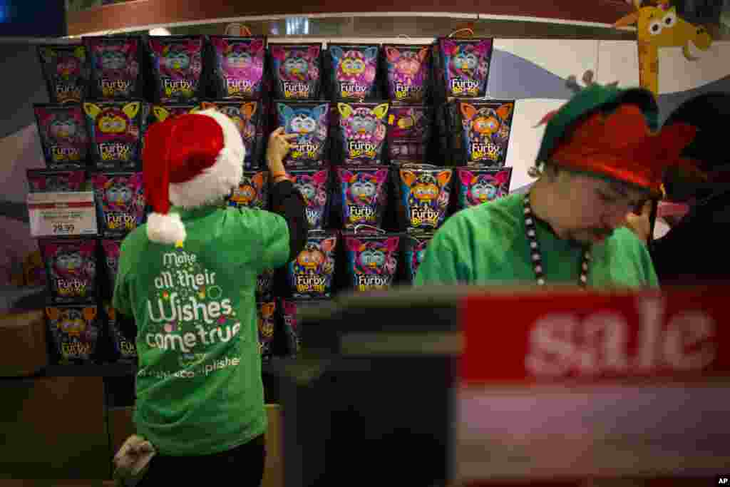 Para pegawai menyimpan persediaan boneka Furby di belakang kasir di toko Times Square Toys R&#39; Us, New York (28/11).&nbsp;(AP/John Minchillo)