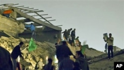 Libyan leader Moammar Gadhafi's supporters inspect damage following an airstrike in Tripoli, April 25, 2011